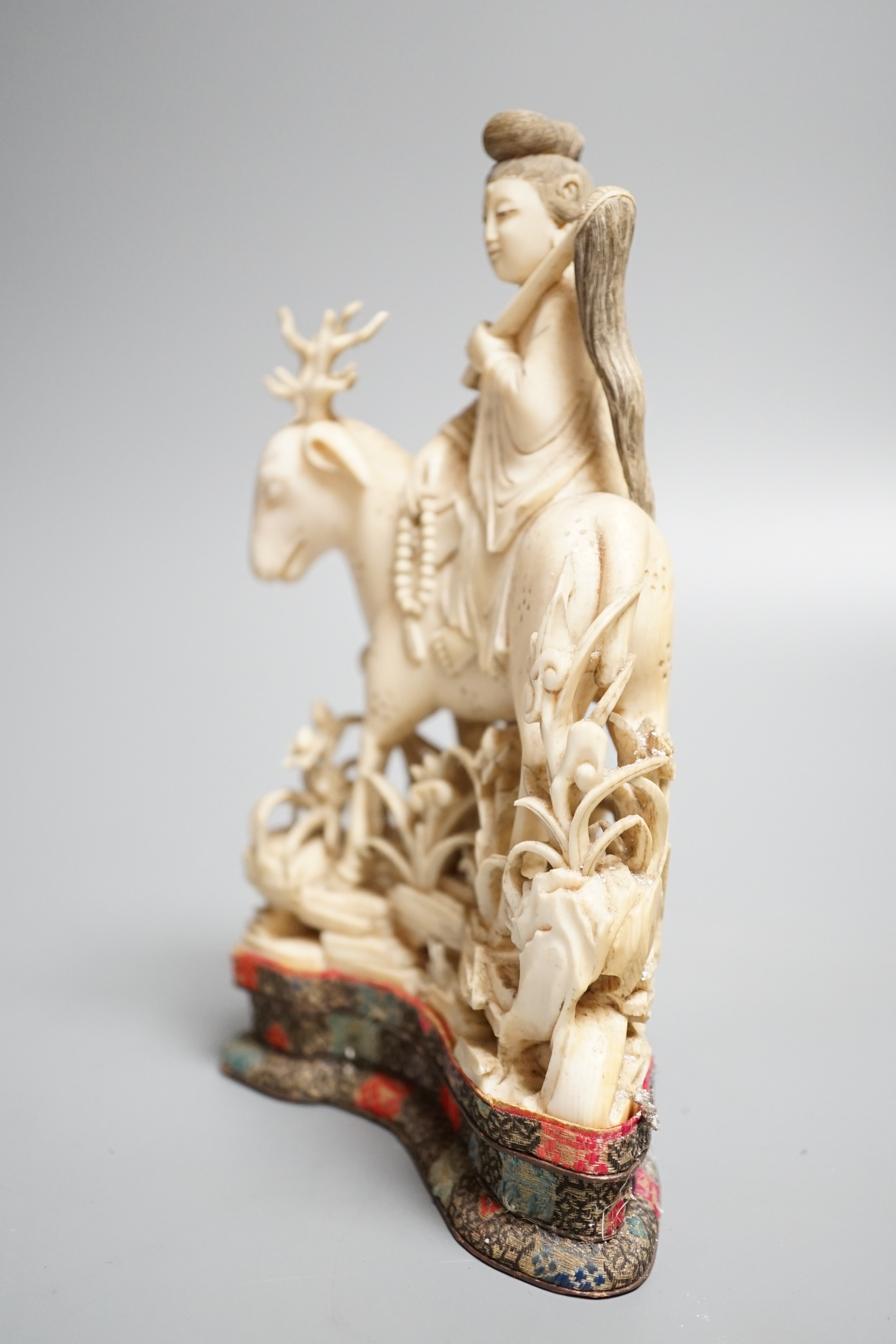 A Chinese carved ivory figure of a female immortal riding a deer, early 20th century, height 17cm excl. stand